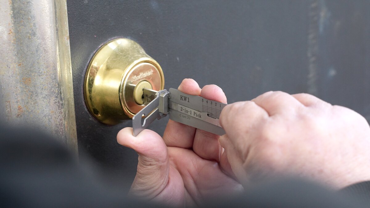Precision Lock & Key technician using a KW1 2-in-1 pick tool on a Kwikset deadbolt — non-destructive entry without damaging the lock