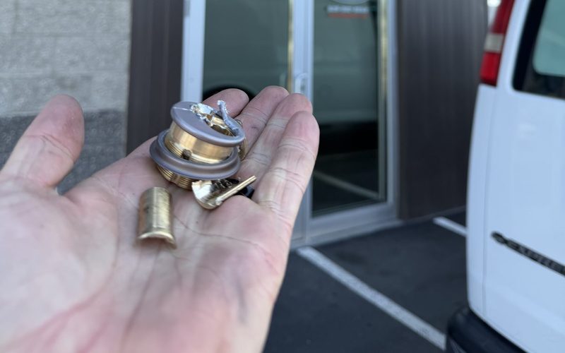 Greg holding destroyed lock cylinder in front of RC Roofing Specialists building in Liberty Lake